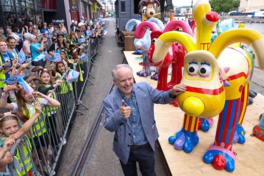 Nick Park, the creator, alongside the steam train carrying numerous Gromit sculptures, including the one inspired by the Yellow Submarine shown here
